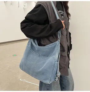 Detail van lichtblauwe denim hobo-tas met verstelbare gesp en grote zak aan de voorkant