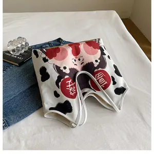 Detail of white canvas tote bag with cute pig cow cartoon print and red joy text labels