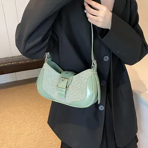 Detail of light green underarm bag featuring textured fabric and gold buckle hardware