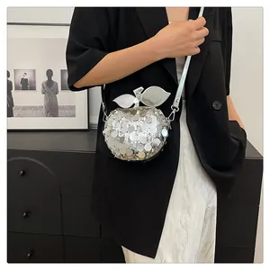 Dettaglio della borsa a tracolla con paillettes argento a forma di mela indossata dal modello