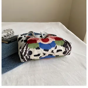 Artistic detail of canvas tote bag featuring colorful abstract face print on white fabric