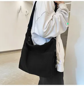 Detailopname van een grote zwarte canvas messenger tas met verstelbare riem en metalen rits