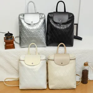 Detail of four quilted faux leather backpacks in silver, black, white, and beige colors