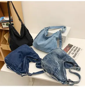 Detailopname van denim hobo-tassen in vier kleuren met verstelbare riemen en metalen gespen