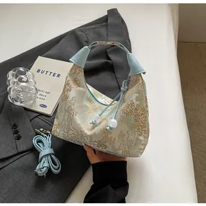 Detail of light blue jacquard dumpling bag with gold landscape embroidery and leather handle