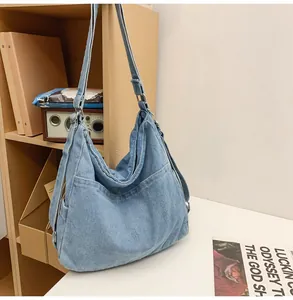 Gedetailleerd beeld van lichtblauwe denim shopper met twee voorzakken en brede banden