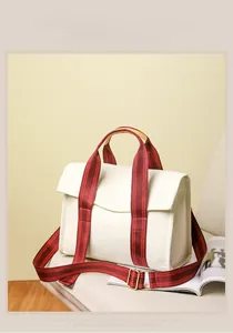 Detail of white canvas tote bag with burgundy striped handles and golden hardware