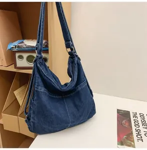 Detailopname van de donkerblauwe denim draagtas met zijvakken en witte contrasterende stiksels