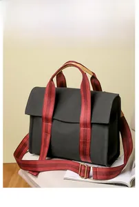 Detail of black canvas tote bag with red striped strap and adjustable buckle detail