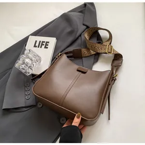 Detail van vintage bruine leren tas met brede riem met geometrisch patroon en matte lak