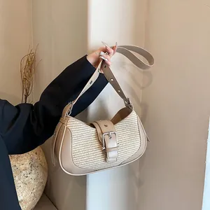 Detail of khaki leather and straw woven shoulder bag held by a model in warm light