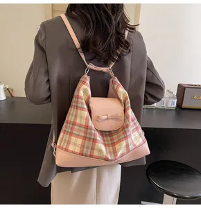 Detail der rosa Lederklappe mit Schleife an einer karierten Canvas-Tasche am Modell