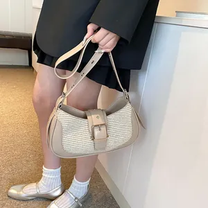 Detailed close-up of woven texture and adjustable buckle on creamy beige underarm bag