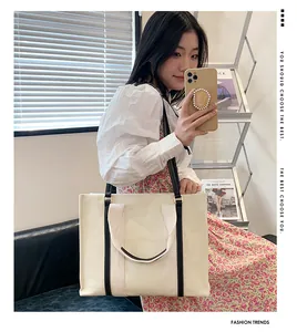 Grand sac cabas en toile avec anses contrastées porté par un mannequin en gros plan