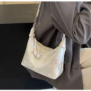 Detail of cream silk satin shoulder bag with vintage floral embroidery and bead charms