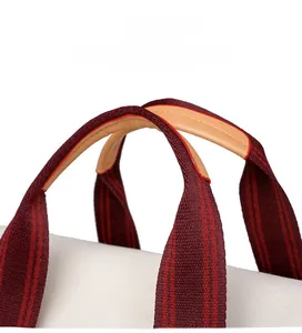 Detail of red and brown striped canvas bag handles with reinforced light brown leather grip