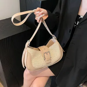 Detail of beige crescent underarm bag with straw texture and silver buckle accents