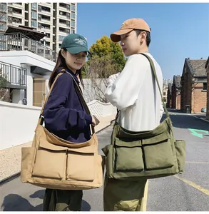 Detail of khaki and olive canvas messenger bags featuring large front utility pockets