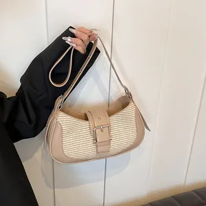 Detail of woven crescent baguette bag featuring beige fabric and faux leather strap