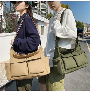 Detail of khaki and army green canvas messenger bags with multi-pocket design on models
