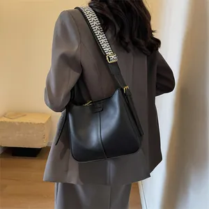 Minimalistische zwarte bucket bag met geweven schouderband en goudkleurige metalen details