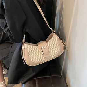 Close-up of beige woven baguette bag with leather strap and silver buckle detail