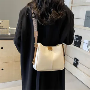 Chique beige schoudertas met brede etnische riem en kwastje getoond op model
