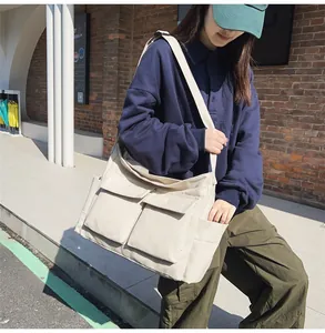 Detail of a beige canvas shoulder bag with functional large front flap pockets