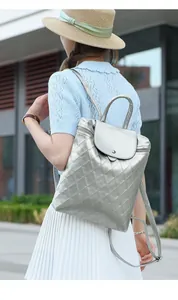 Outdoor shot of a shiny silver quilted backpack with a flap top and metal clasp detail