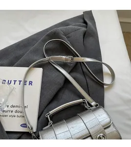 Détail d'un sac messager argenté en PU avec texture craquelée et fermoir en métal