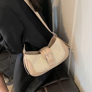Close-up of beige woven baguette bag with brown leather strap on model in black suit