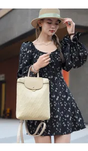 Close-up of a beige quilted backpack with magnetic flap worn with a floral dress