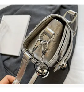 Détail d'un sac à bandoulière en cuir argenté avec ferrures et pendentif sphérique