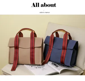 Detail of khaki and navy canvas tote bags with striped wide ribbon handles on a chair