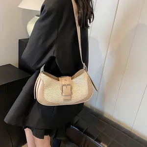 Detail of the woven texture and metal buckle on the beige shoulder bag worn by a model