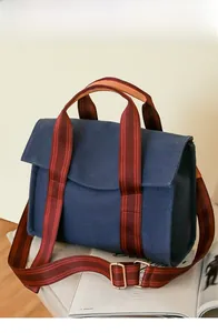 Close-up of navy canvas tote bag with adjustable striped shoulder strap and flap closure