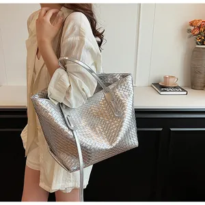 Grande borsa tote intrecciata argento metallizzato indossata a spalla con doppie maniglie