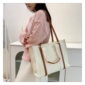 Détail du sac cabas en toile montrant la conception à double sangle et les poignées en cuir