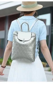 Rear view of a silver quilted backpack with metallic finish on a female model outdoors
