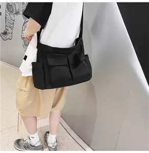 Detail view of black canvas crossbody bag with large front pockets on a model