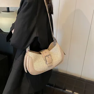 Detail of beige woven baguette shoulder bag featuring faux leather trim and silver buckle