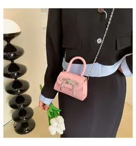 Detail of pink mini bag with rhinestone bow and silver chain worn with a blazer
