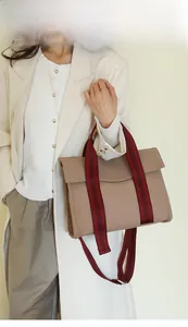 Close-up of khaki canvas tote bag with red and brown striped strap for office use
