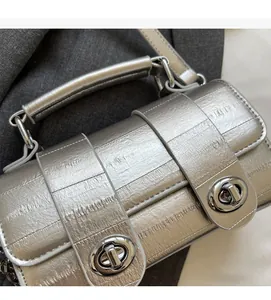 Vue détaillée du sac bandoulière argenté avec double fermoir rotatif et poignée