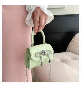 Detail of mint green mini handbag with rhinestone bow decoration and silver metal chain