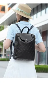 Rear view of a chic black quilted backpack with silver clasp on a stylish model