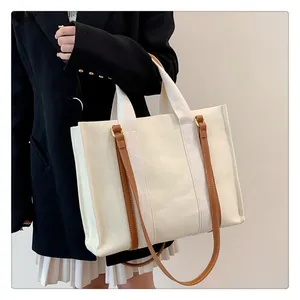 Gros plan du cabas en toile avec bandoulières en cuir marron sur un costume noir