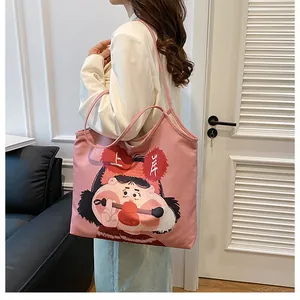 Detail view of pink canvas tote bag featuring cute cartoon print and long shoulder straps
