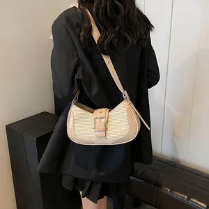 Close-up of beige woven leather shoulder bag with metal buckle and adjustable strap