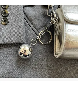 Gros plan d'un pendentif boule en métal argenté sur un sac à main argenté motif crocodile